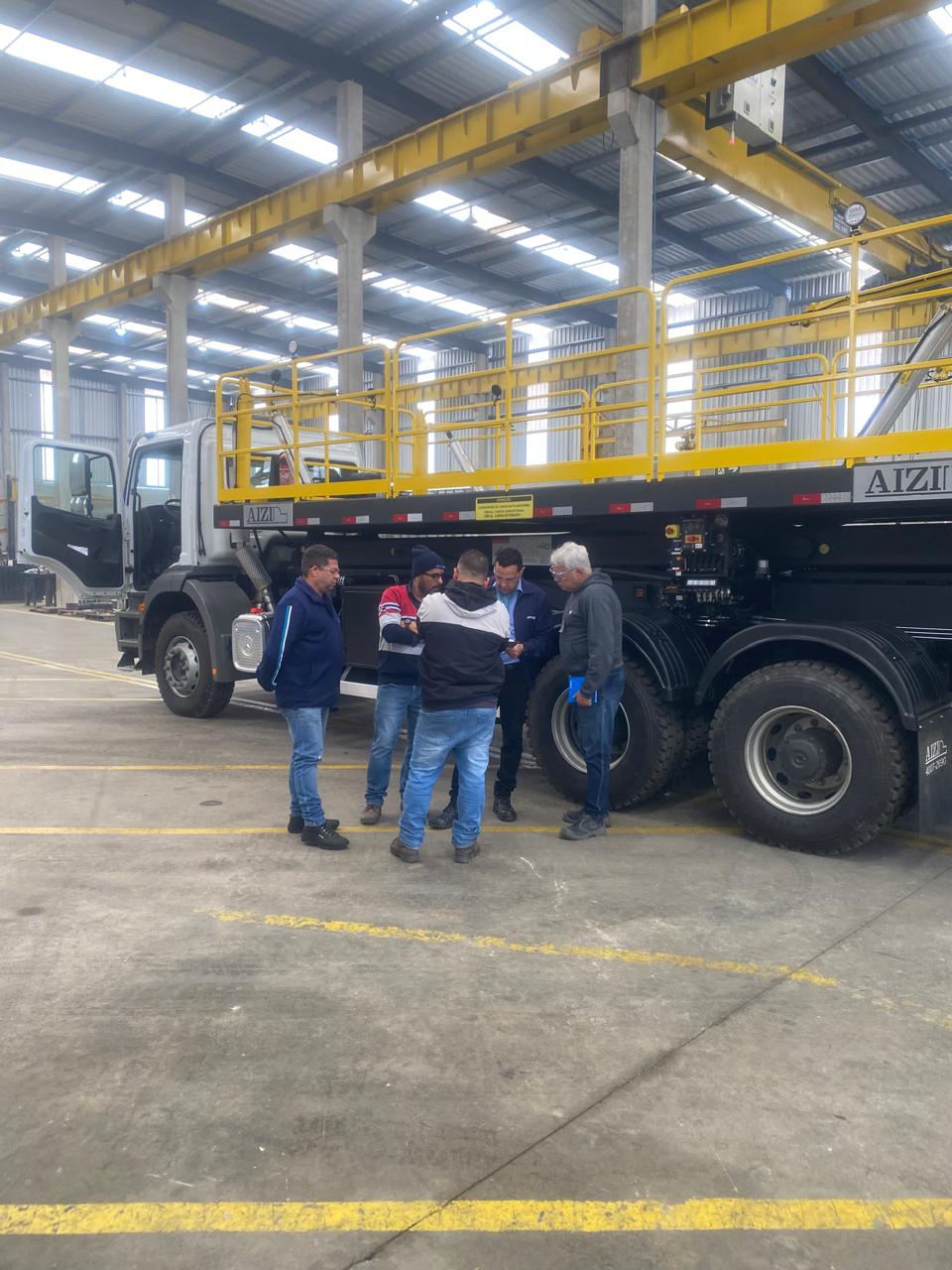 Equipe técnica avaliando a plataforma pantográfica montada sobre o chassi